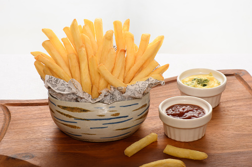 a bowl with a portion of fries, katcup and mustard sauce on a white background
