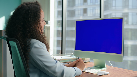 Side view of woman using green screen of computer monitor in home office.