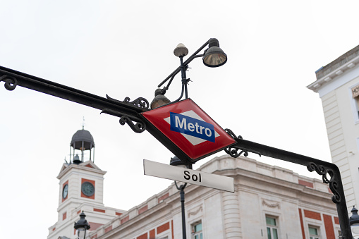 Madrid, Spain: 03/30/2023: Metro sign at the Puerta de Plaza del Sol in the city of Madrid, Spain. With buildings of the city in the background.