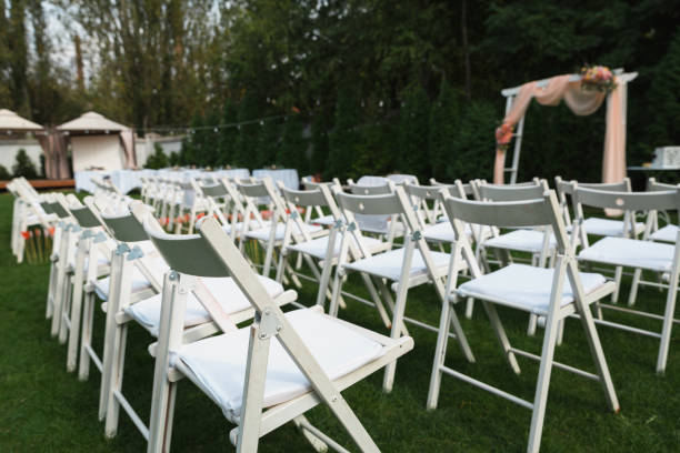 istock Wedding chairs set up before the ceremony. Rows of white empty chairs on a lawn before a wedding or ceremony. 1482213019