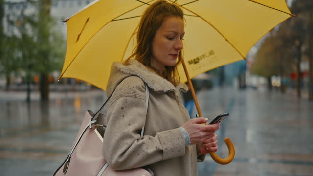 SLO MO Freckled young woman types on her smartphone in a rainy city