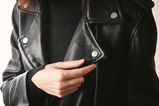 Woman leather jacket design concept on hanger holding. Woman in black leather jacket.