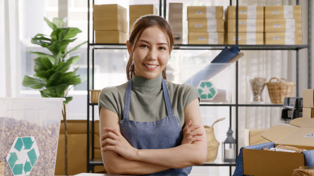 istock Go green use eco friendly packaging box in net zero waste store asian seller retail home office shop. Small SME owner young adult asia Gen Z people happy relax smile pride arm cross looking at camera. 1482221371