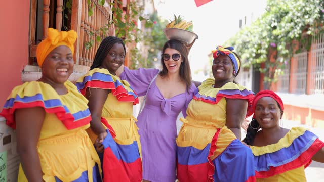 Portrait of mid adult tourism woman with palenqueras on the street in Cartagena, Colombia