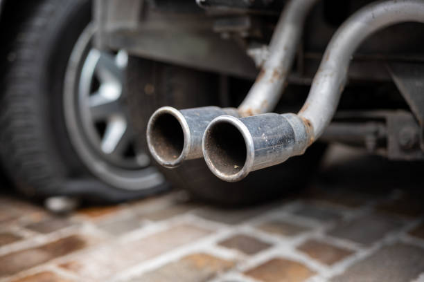 viejas puntas de escape de automóviles cromadas oxidadas colgando de un automóvil desmembrado. espectáculo de ángulo bajo, enfoque selectivo, sin personas - dismembered fotografías e imágenes de stock