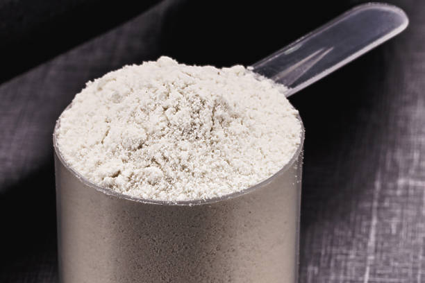 istock casein in measuring spoon, black background with weights and weight training dumbbells, macrophotography 1482222860