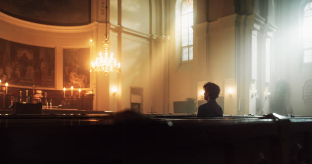 istock A Devout Christian Sits Piously In A Grand Church, Folding Hands for Praying, Contemplating Their Earthly Life. Parisher Seeks Moral Guidance From the Faith. Religious Atmosphere Of The Sacred Space 1482225030