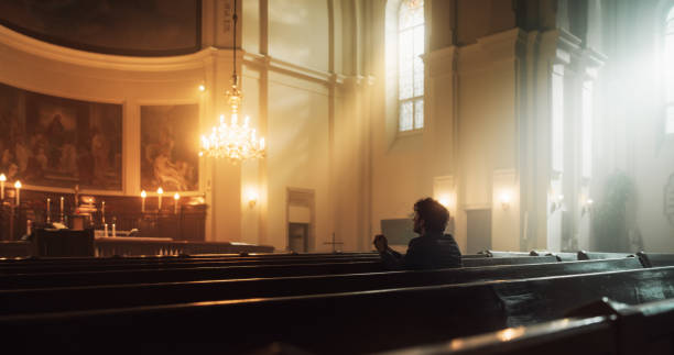 istock A Devout Christian Sits Piously In A Grand Church, Folding Hands For Praying, Seeks Guidance From Their Religious Faith and Spirituality. Spirit of Christianity and Belief in Power and Love of God 1482225062