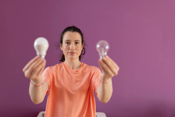 istock Comparison economic and normal light bulb. Smiling woman comparing energy saving light bulb with incandescent lamp 1482226225