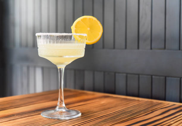 Alcohol cocktail Margarita with slise of lime on wooden table against dark wall with copy space stock photo
