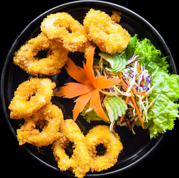istock Fried squid or calamari in batter on a black plate close up top view 1482226877