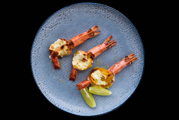 istock Grilled shrimps with cheese on blue plate isolated on black background top view 1482227848