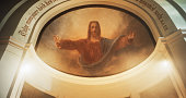 Mural Portrait of Lord Jesus Christ with Open Arms. A Painting on a Church Ceiling Depicting the Savior's Kindness and Acceptance of Devoted Believers. The Devine Light Shining Upon his Face