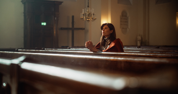 Portrait of a Young Woman Praying in the Majestical Old Church. Parishioner Feeling the Connection to the Divinity. Hope and Belief in Salvation through Goodness, Kindness. Contemplation in Cathedral