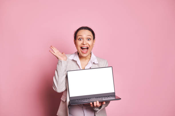 istock Surprised multi ethnic woman with her mouth open, holding laptop with white blank screen, isolated on pink background 1482229065
