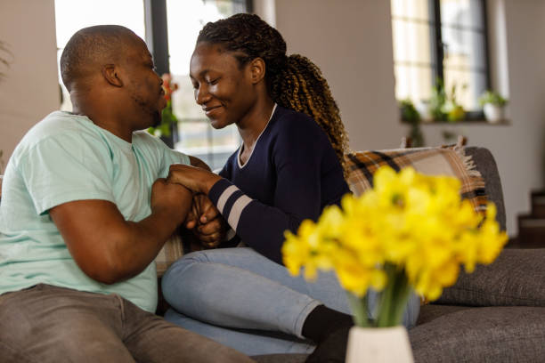 istock Romantic couple holding hands and smiling at each other while lounging on the sofa 1482232496