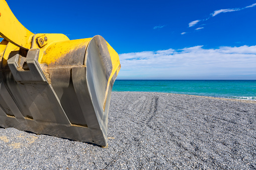 Borghetto Santo Spirito (SV), Italy, excavator working and levelling the beach at sea