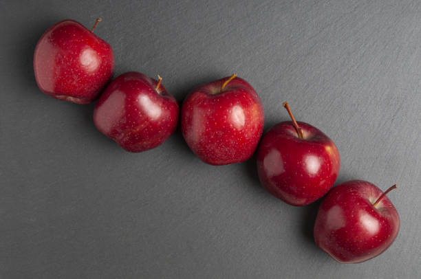 Row red ripe apples on a black background