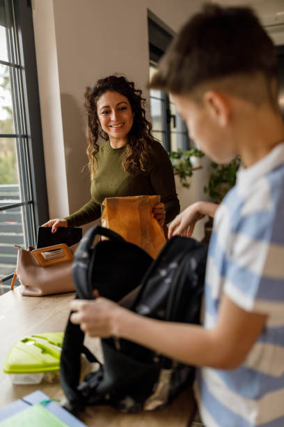 istock Teenage boy packing his school backpack while his mother is preparing for work 1482240143