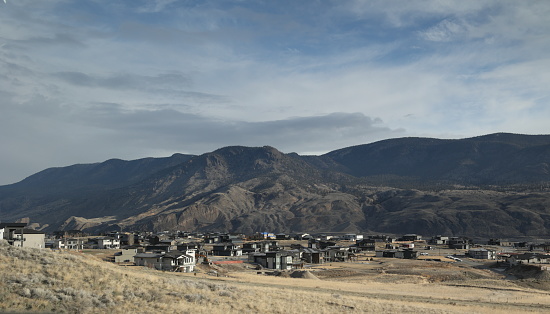 Upscale houses stand between the Trans-Canada Highway and Kamloops Lake in the Thompson-Nicola Regional District. This community is west of Kamloops. Spring morning with dramatic clouds.