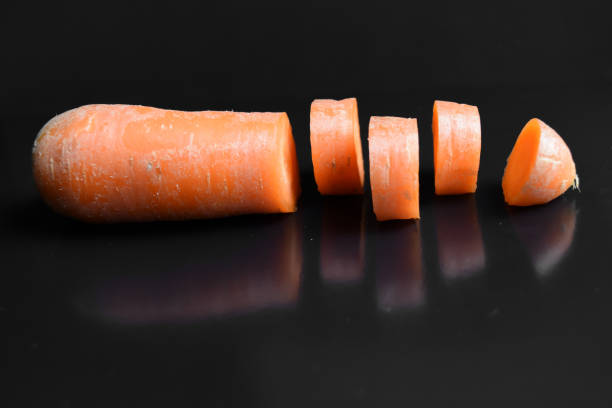 an object of a carrot that has been cut into pieces and has a black background.