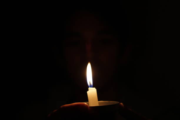 istock The Light in the Darkness: A Hand Holding a Candle 1482244483