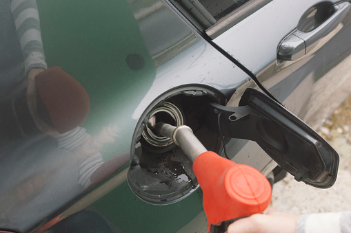 Adult woman refueling car on petrol station
