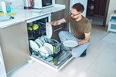 Adult man unloading dishwasher machine