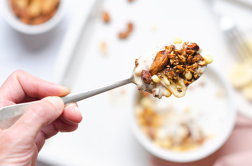 Granola with nuts and dried banana on a spoon. Selective focus.