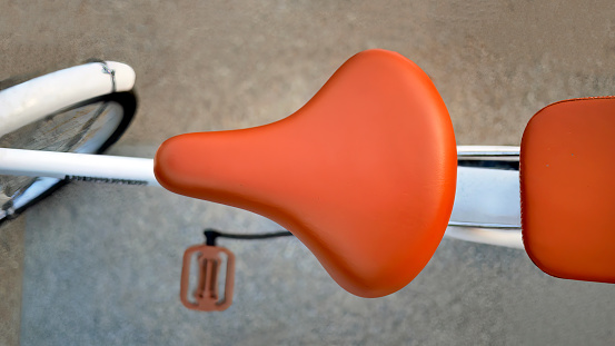 Directly above, top view vibrant brown leather color of bicycle saddle, bicycle seat, selective focus, blurred background, bokeh, vintage, retro, element