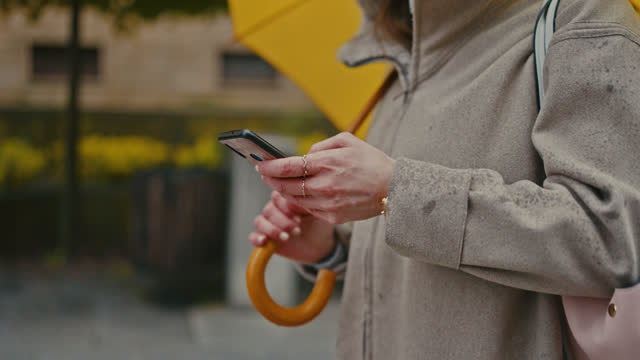 SLO MO Young woman types on her smartphone in a rainy city