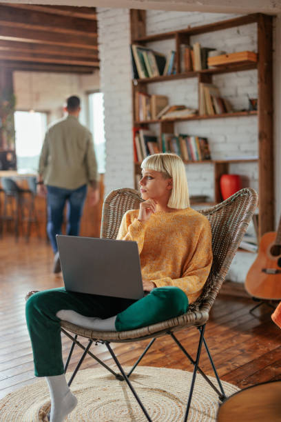 istock Cheerful young woman using laptop in living room. 1482260932