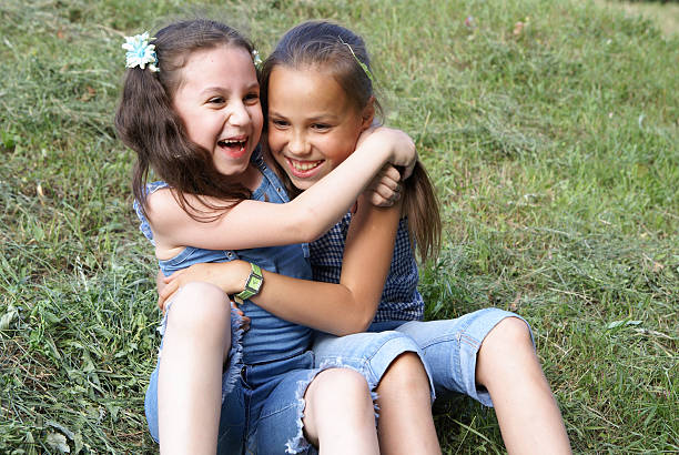 Group portrait of three smiling children lying down on the grass  in the sunny day outdoor.