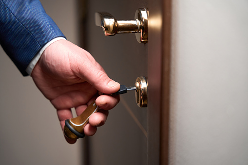 Male in business suit with his hand inserting key into the keyhole in the hostel