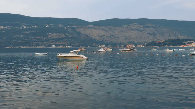 Sea vacation. Boats float on Adriatic Sea. Mediterranean travel business. Hotels and buildings. Road to Igalo. Fire and smoke in forest on mountain. Buoys on the water