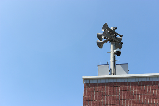 Close-up on a side wall of a building with chimney, antenna, and deep blue sky beyond.