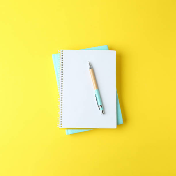 istock Notebooks and pen on yellow background, top view 1482285906