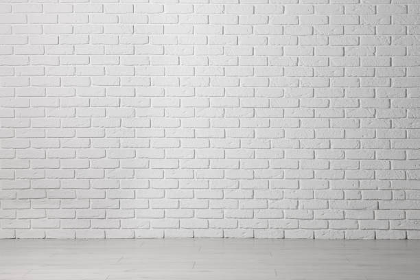 istock Beautiful white brick wall and wooden floor in clean empty room 1482286037