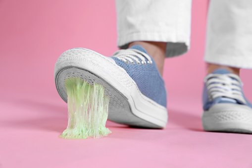 Person stepping into chewing gum on pink background, closeup