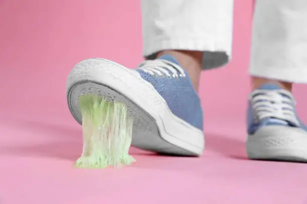 Photo of Person stepping into chewing gum on pink background, closeup