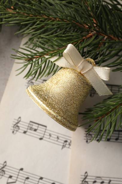 istock Golden shiny bell with bow, music sheets and fir branches on light table, flat lay. Christmas decoration 1482286688