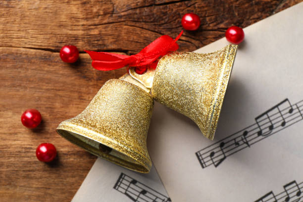 빨간 활과 나무 테이블에 악보가 있는 황금빛 반짝이는 종, 평평하게 누워 있습니다. 크리스마스 장식 - bell jingle christmas music 뉴스 사진 이미지