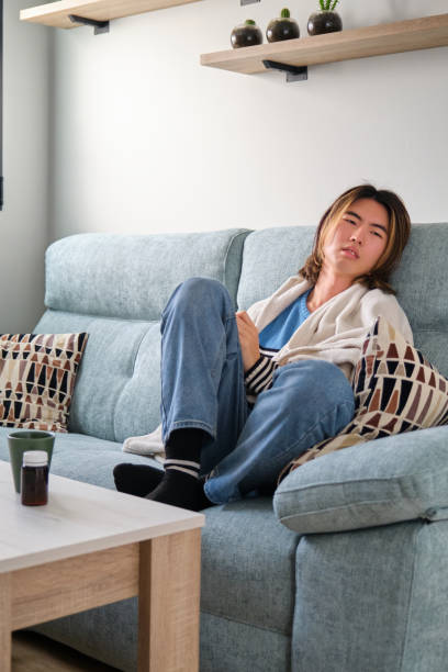 istock Sick taiwanese man resting on a sofa with a blanket. 1482288469