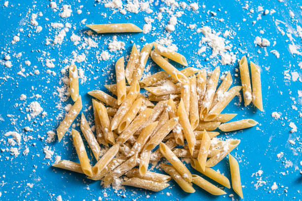 Fresh made penne macaroni on blue background. Cooking pasta concept.Top view