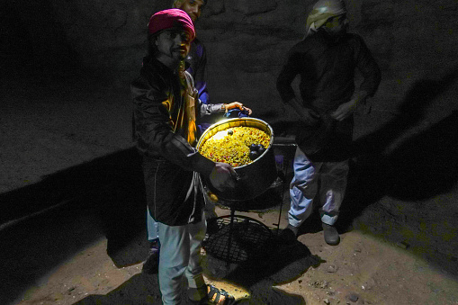 Wadi Rum, Jordan March 25, 2023  Bedouin men at a campsite in the desert present rice and lamb long-cooked underground in the sand to their guests.