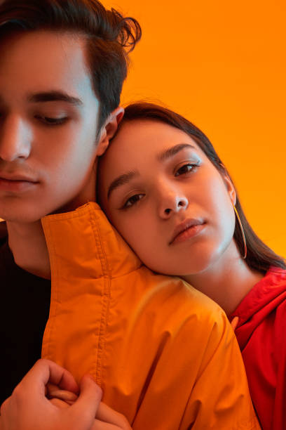 Cool teen couple hugging in studio