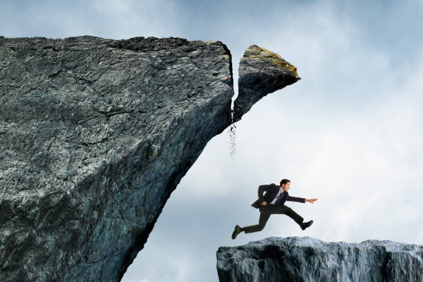 человек бежит от надвигающейся катастрофы - cliff finance risk uncertainty стоковые фото и изображения