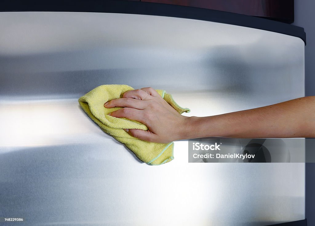 Polishing stainless steel Woman's hand with microfiber cloth polishing a stainless steel fridge door Cleaning Stock Photo