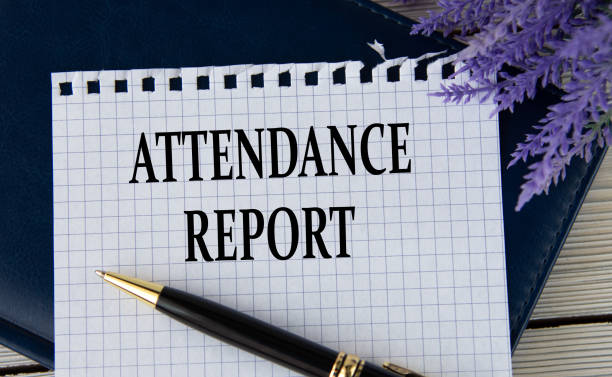 istock ATTENDANCE REPORT - words on a white sheet with a black notepad and pen 1482303550