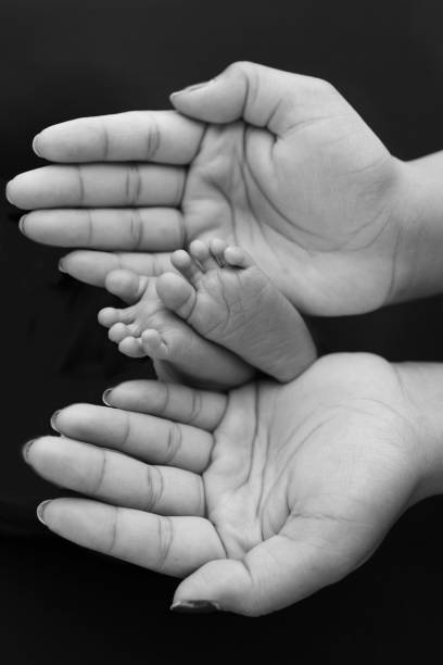 noir et blanc nuance belle forme mains de mère, tenir de minuscules pieds de nouveau-né sur fond noir avec amour, soins, sécurité et protection de la famille, concept d’enfant avec naissance prématurée ou soins de l’usin - 7654 photos et images de collection